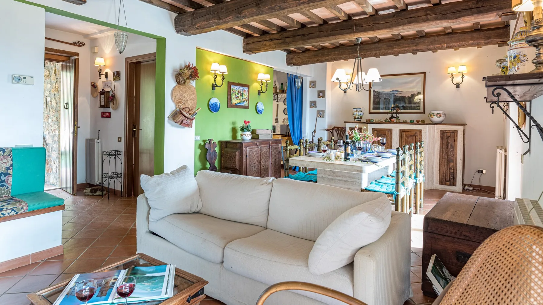 Una sala de estar con asientos claros y vigas de madera expuestas en el techo.