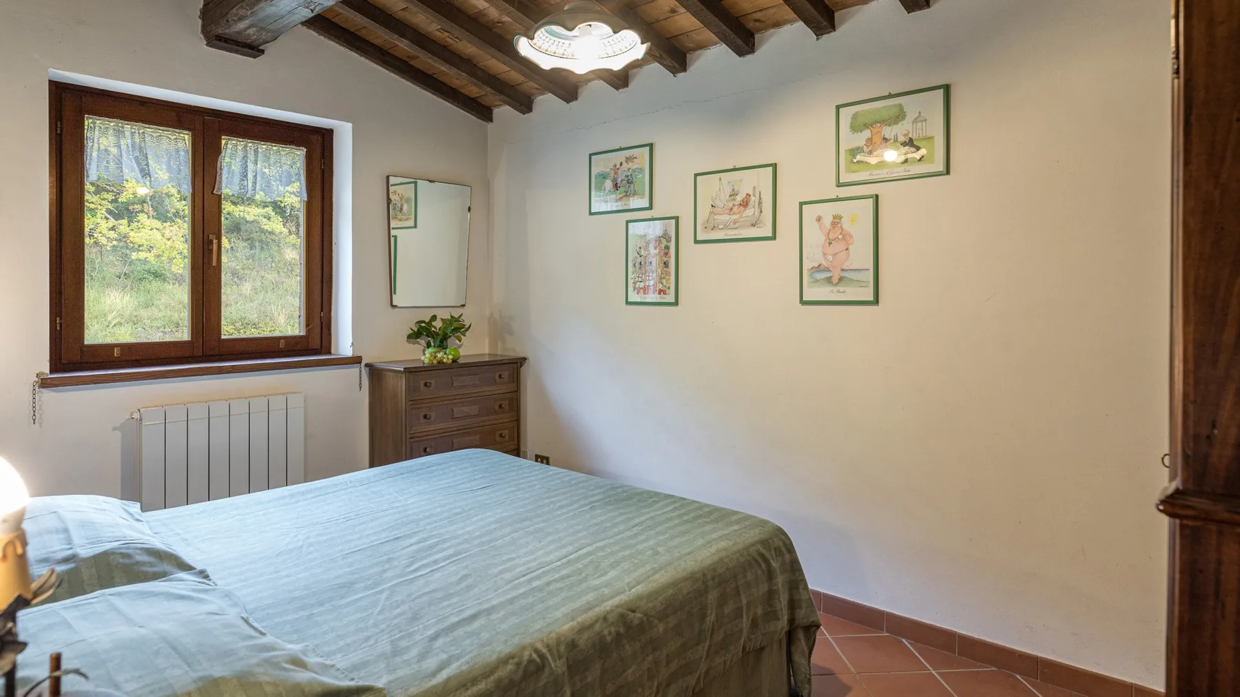 Un dormitorio con una cama bajo un techo con vigas de madera y cuadros en la pared.