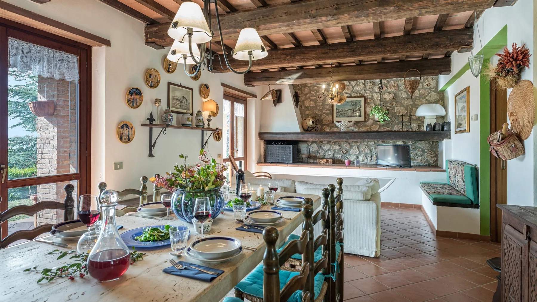 Un comedor con una mesa puesta y una chimenea de piedra al fondo.