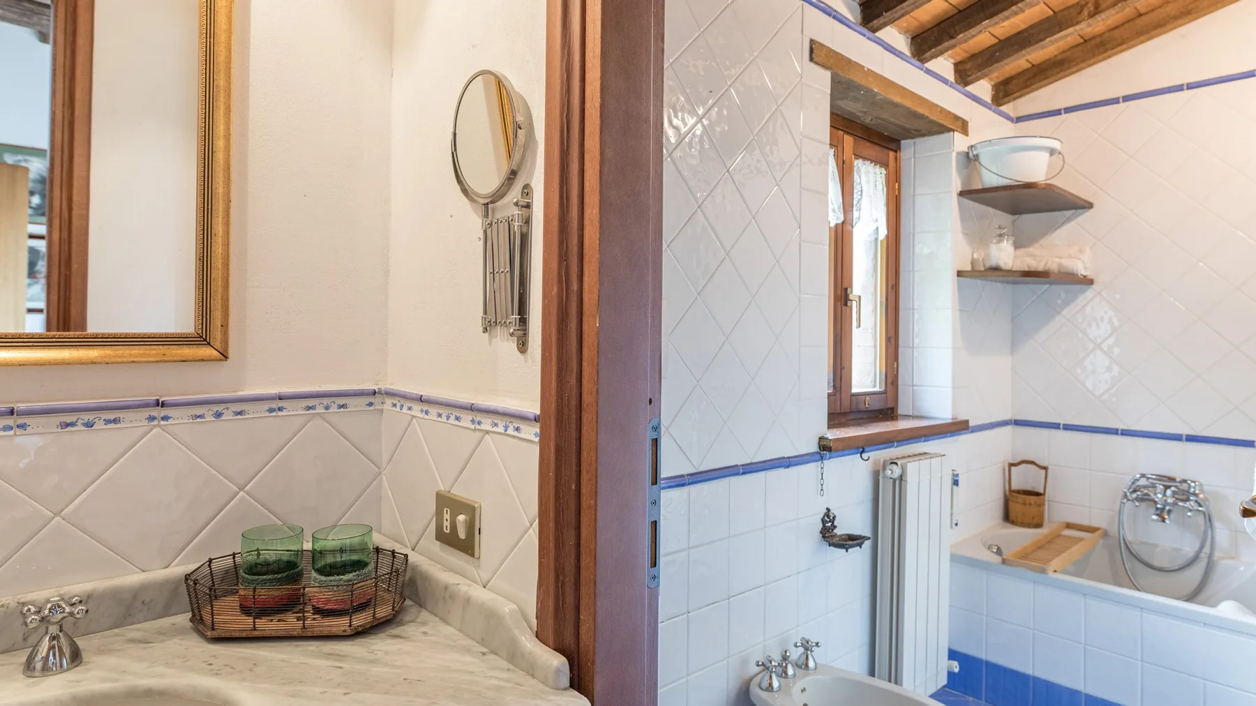 Un baño con azulejos, bañera, ventana y estantes abiertos.
