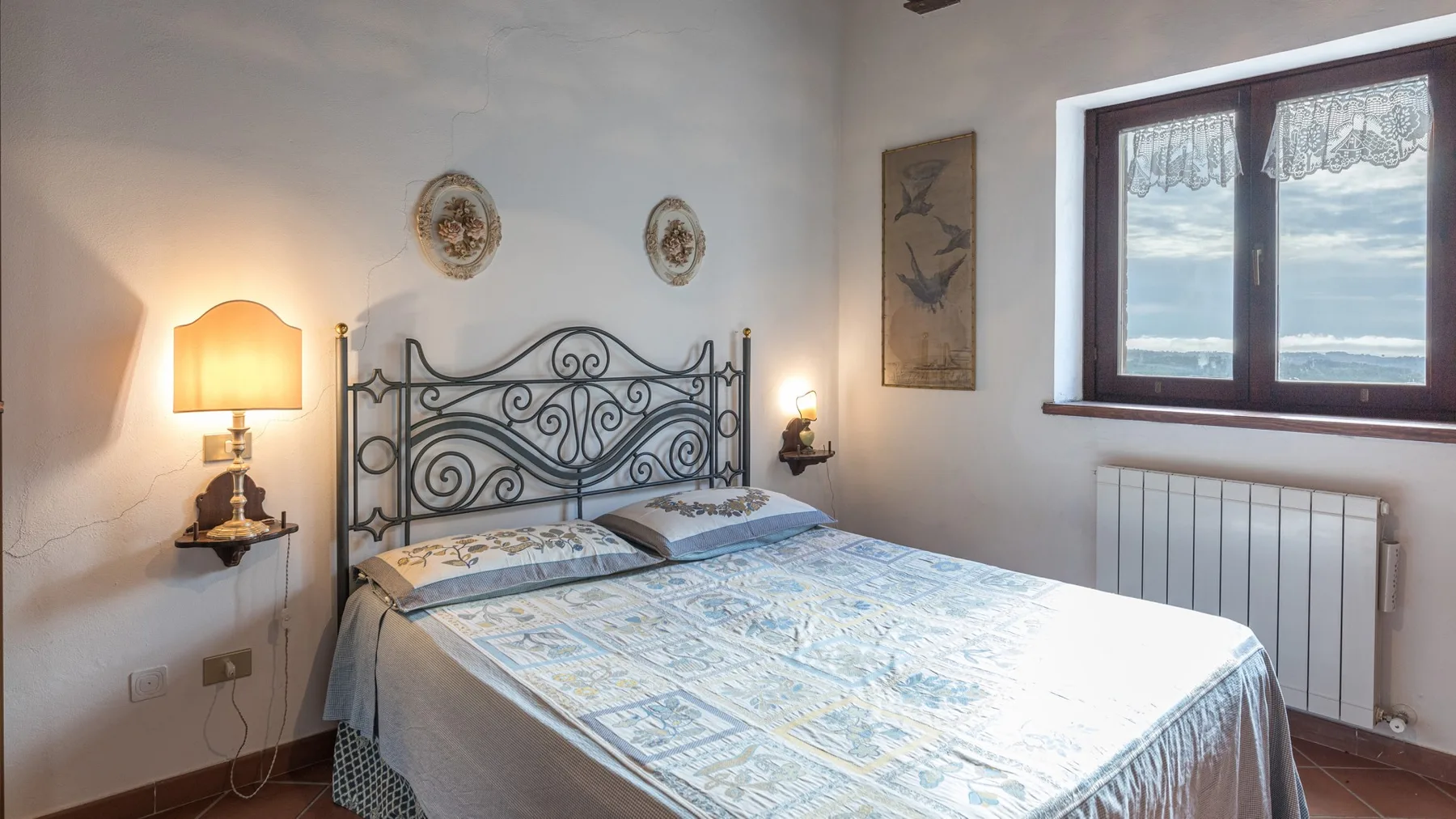 Un dormitorio con una cama de hierro forjado y una ventana con vistas al mar.