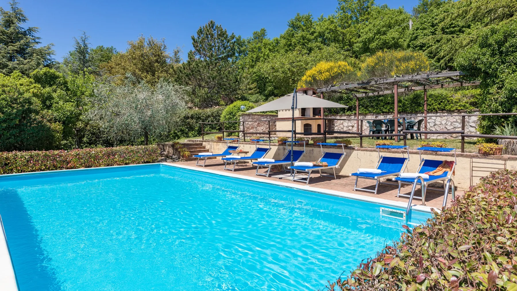 Una piscina al aire libre con tumbonas azules en la terraza.