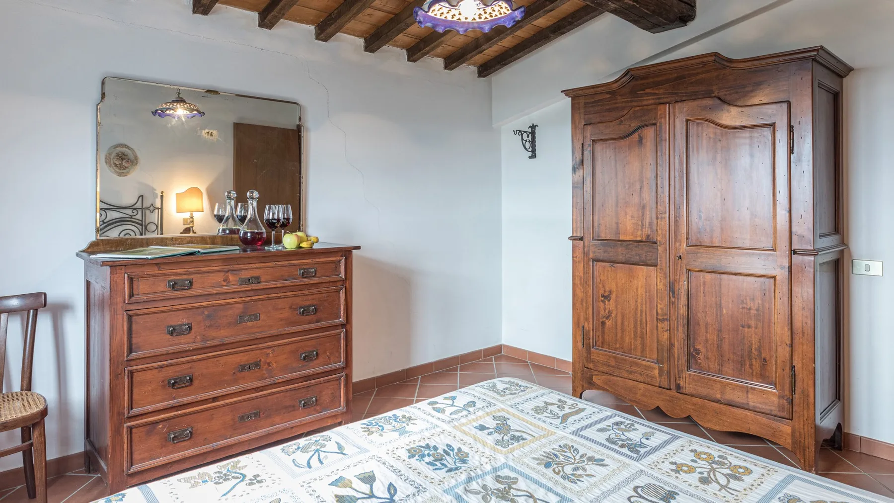 Un dormitorio con armario de madera, cómoda y baldosas estampadas.