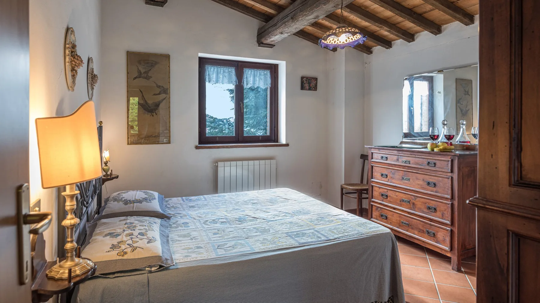 Un dormitorio con una cama tendida, vigas de madera en el techo y una cómoda.