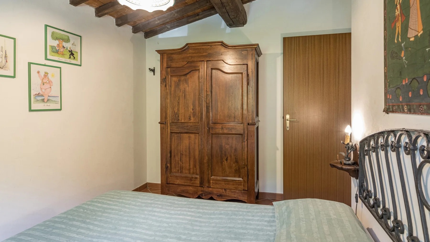 Un dormitorio con un armario grande de madera, una cama y cuadros enmarcados.