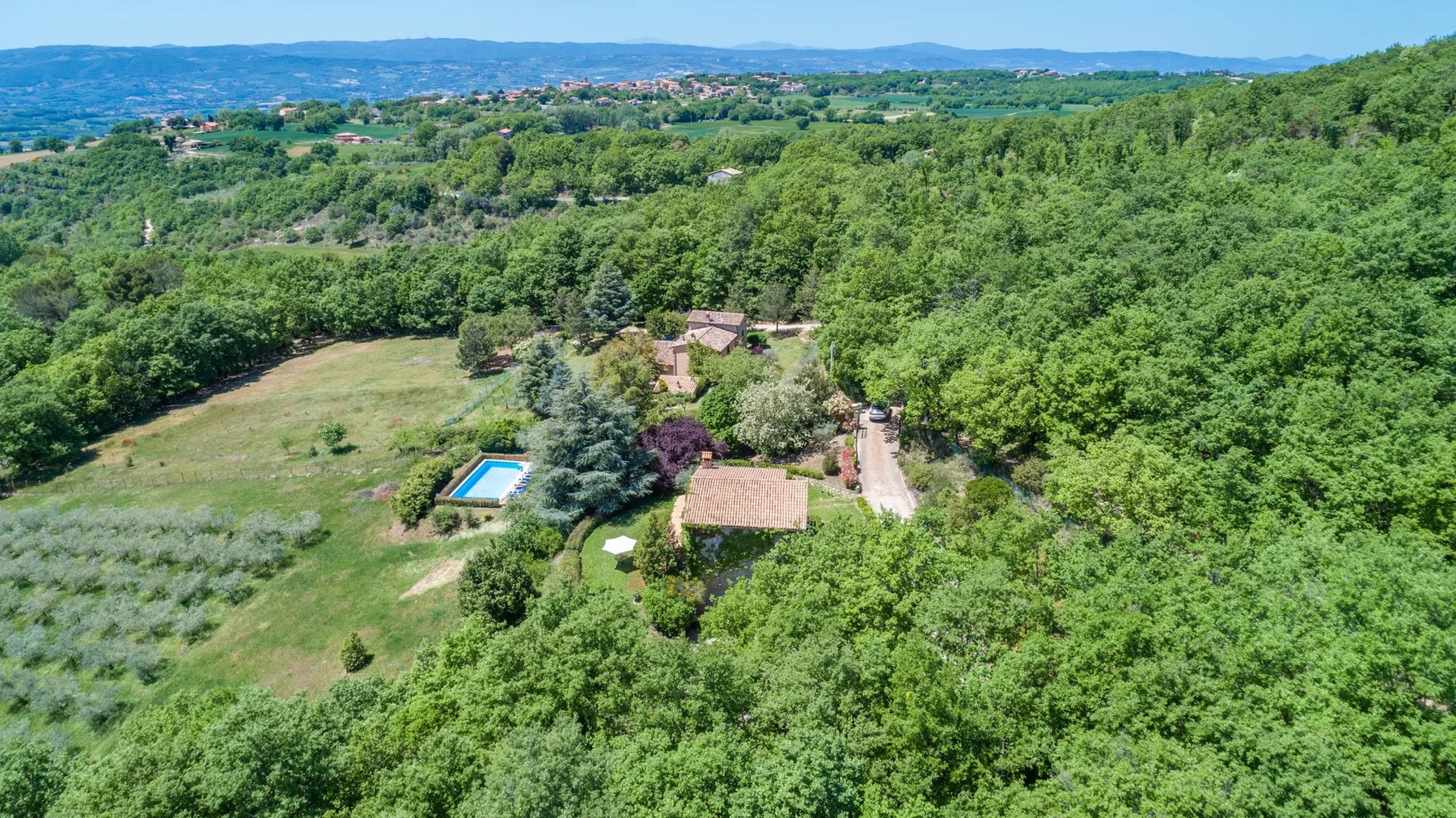 Vista aérea de una propiedad rural boscosa con una pequeña piscina.