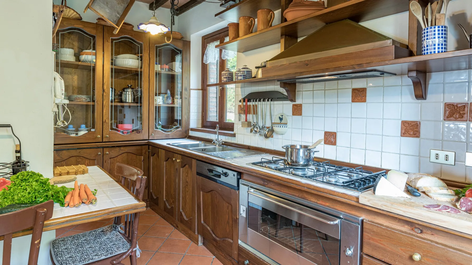 Una cocina con gabinetes de madera, un salpicadero de azulejos y una encimera larga.