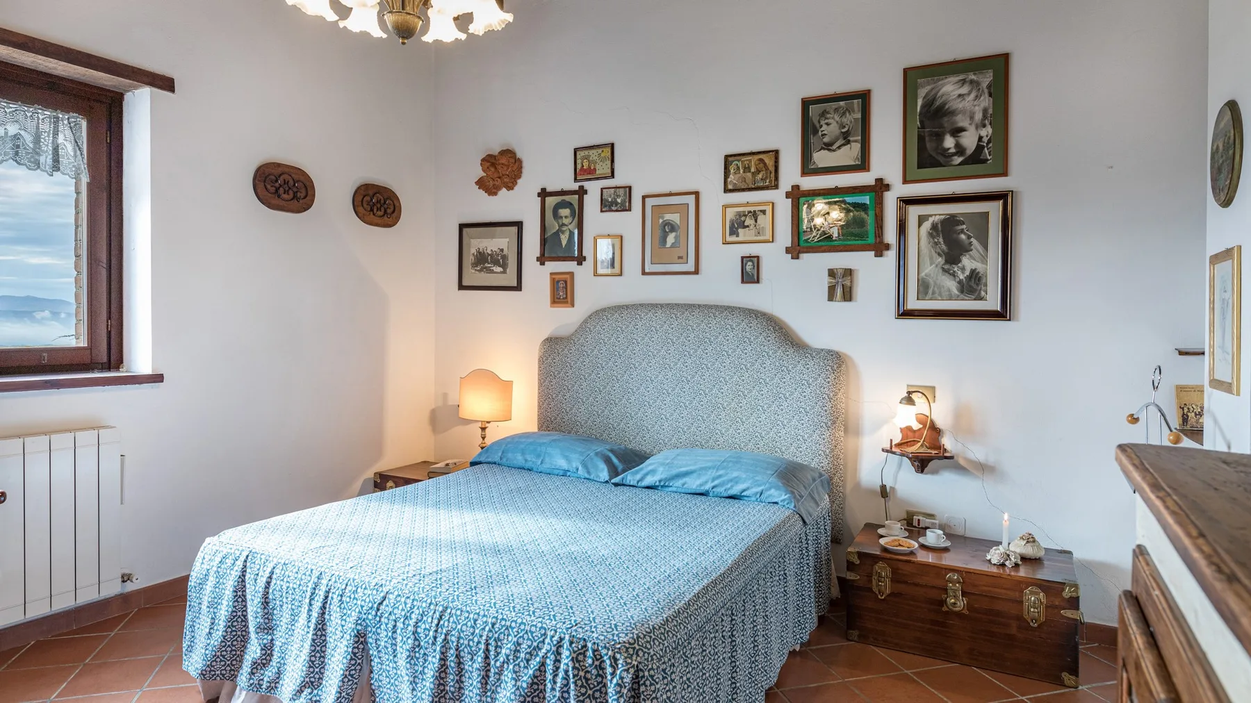 Un dormitorio con una cama cubierta de azul y cuadros en la pared.