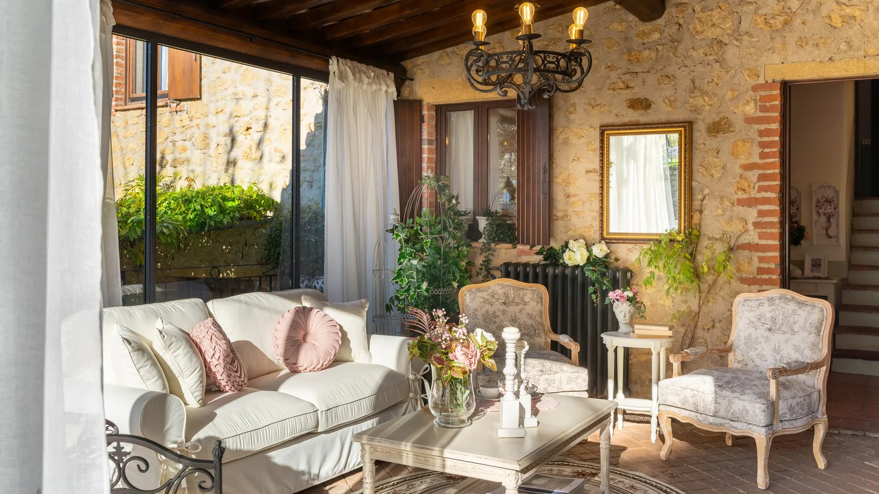 Sala de estar con paredes de piedra, asientos claros y una mesa baja.