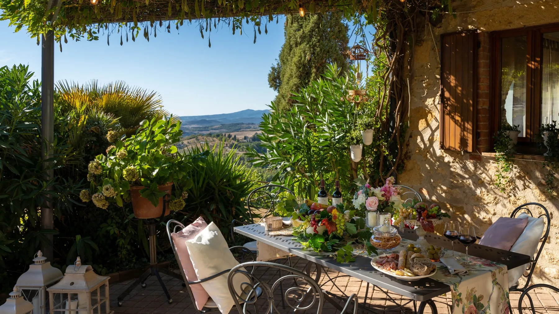 Un comedor al aire libre tiene una mesa con flores y vistas a las colinas cercanas.