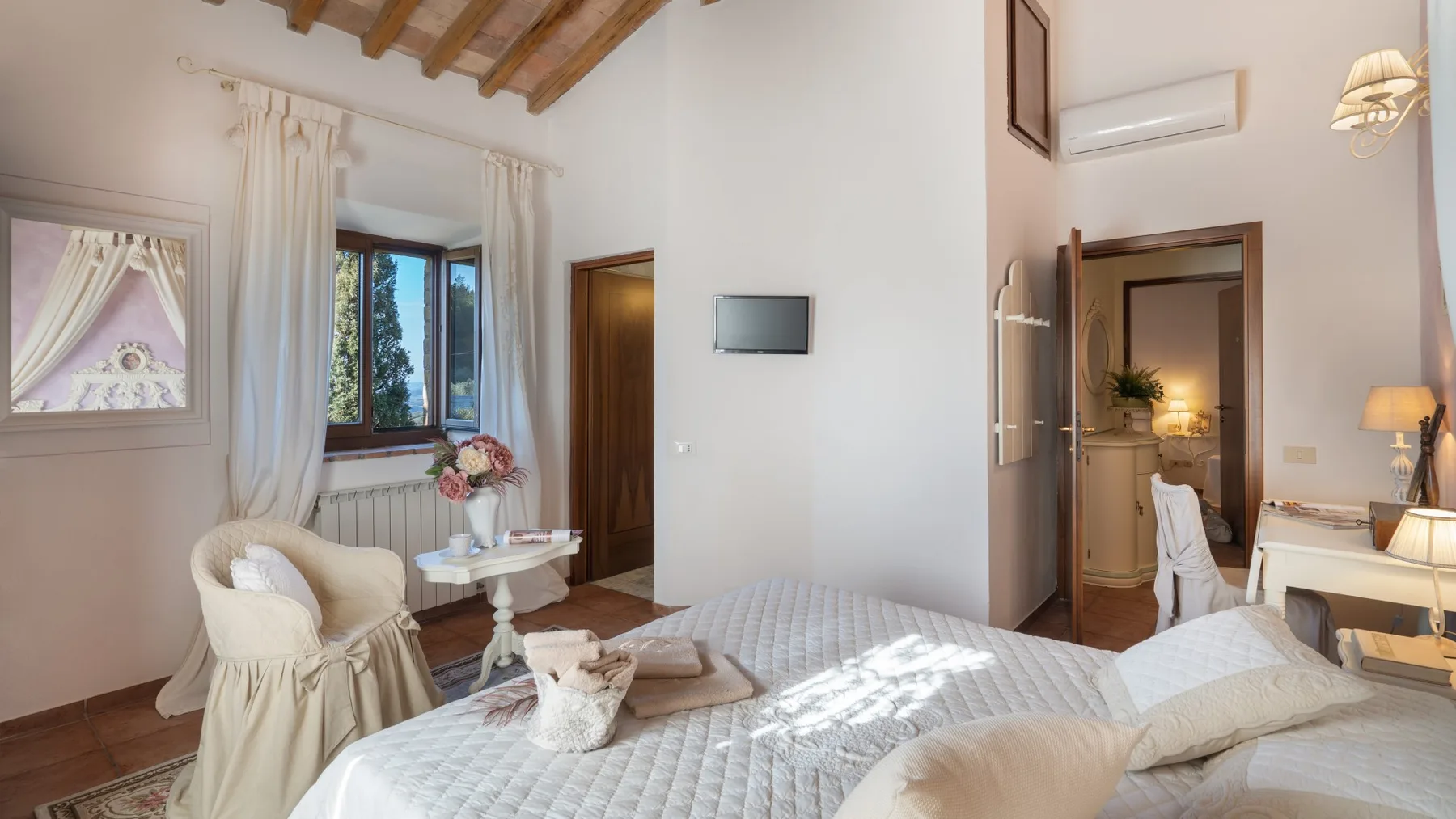 Un dormitorio con una cama grande, una ventana con cortinas y vigas de madera a la vista.