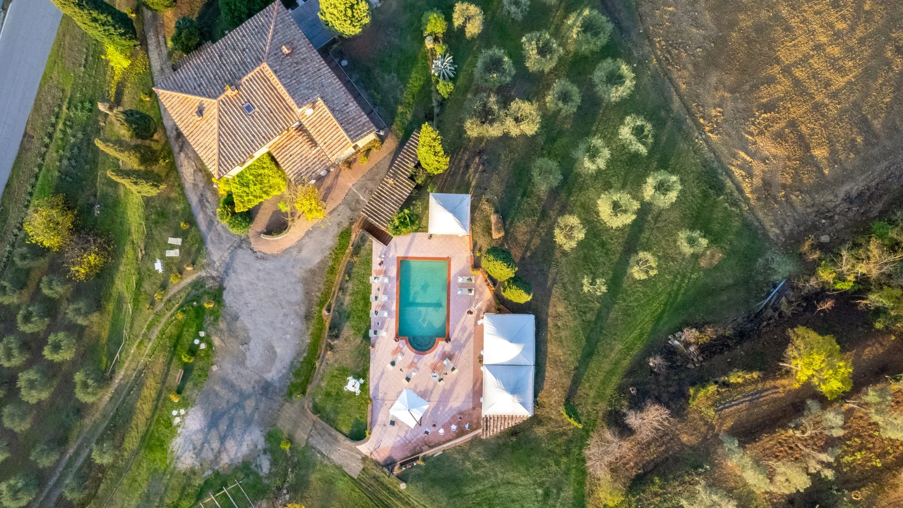 Vista aérea de una casa, una piscina y los jardines que la rodean.