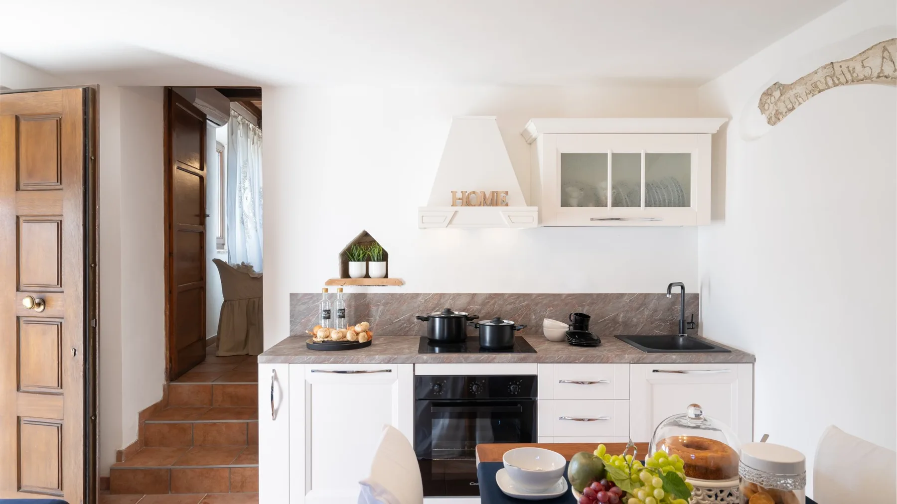 Una cocina luminosa con gabinetes blancos, una encimera y electrodomésticos.
