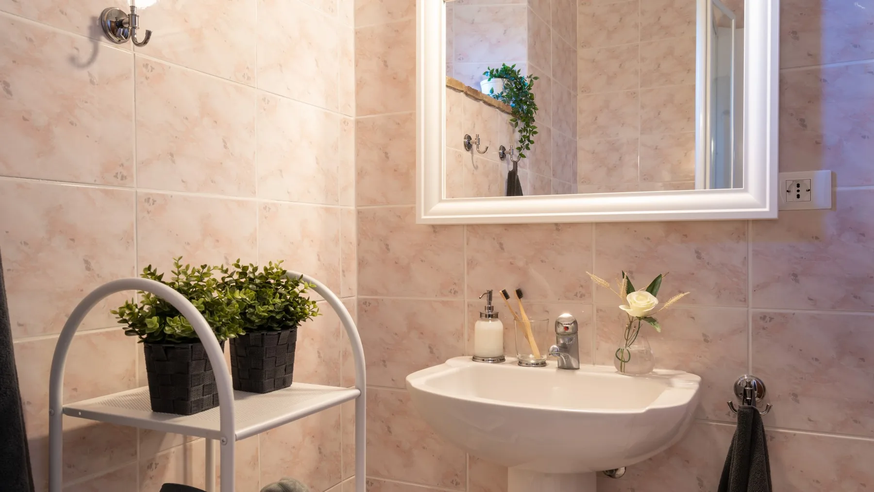 Un baño con azulejos, lavabo de pared y espejo.
