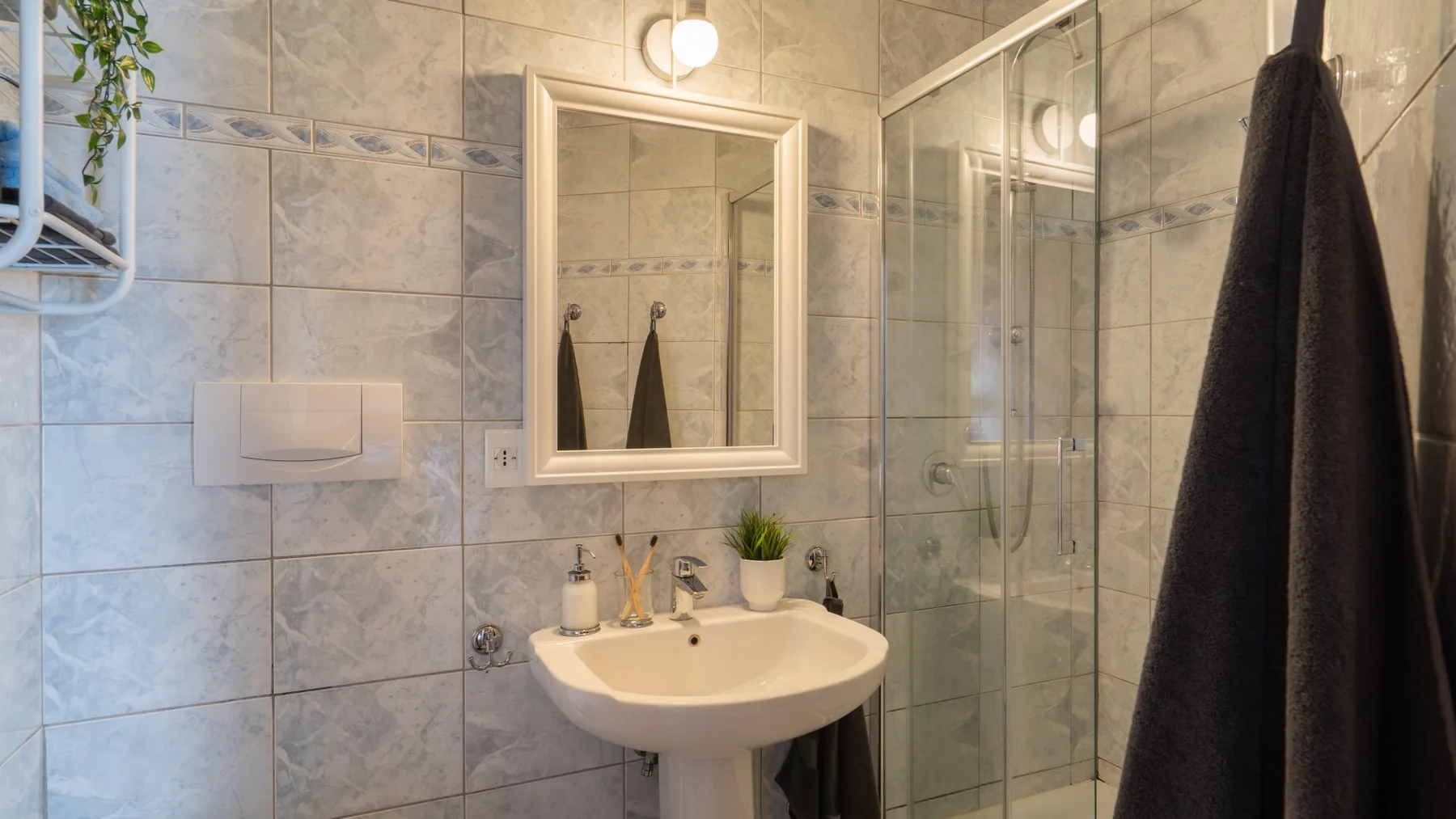 Un baño con azulejos, lavabo de pedestal y ducha de vidrio.