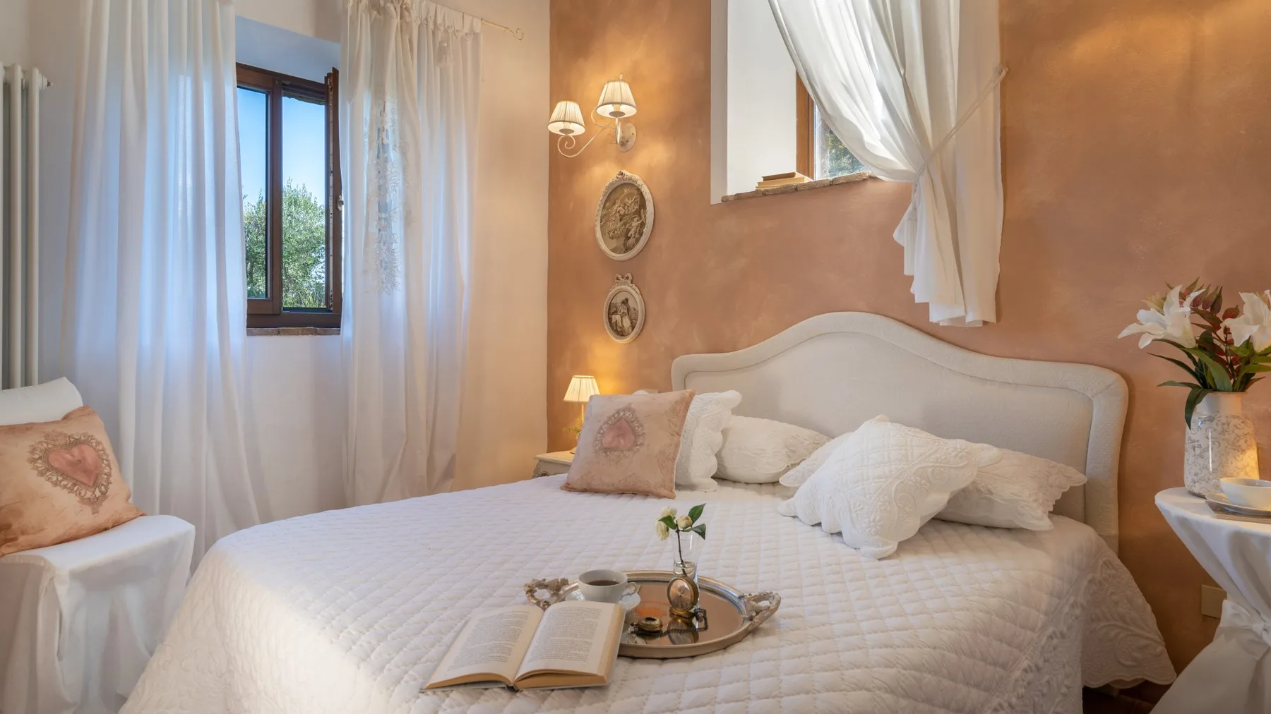 Un dormitorio con una cama bien tendida y cortinas traslúcidas junto a la ventana.