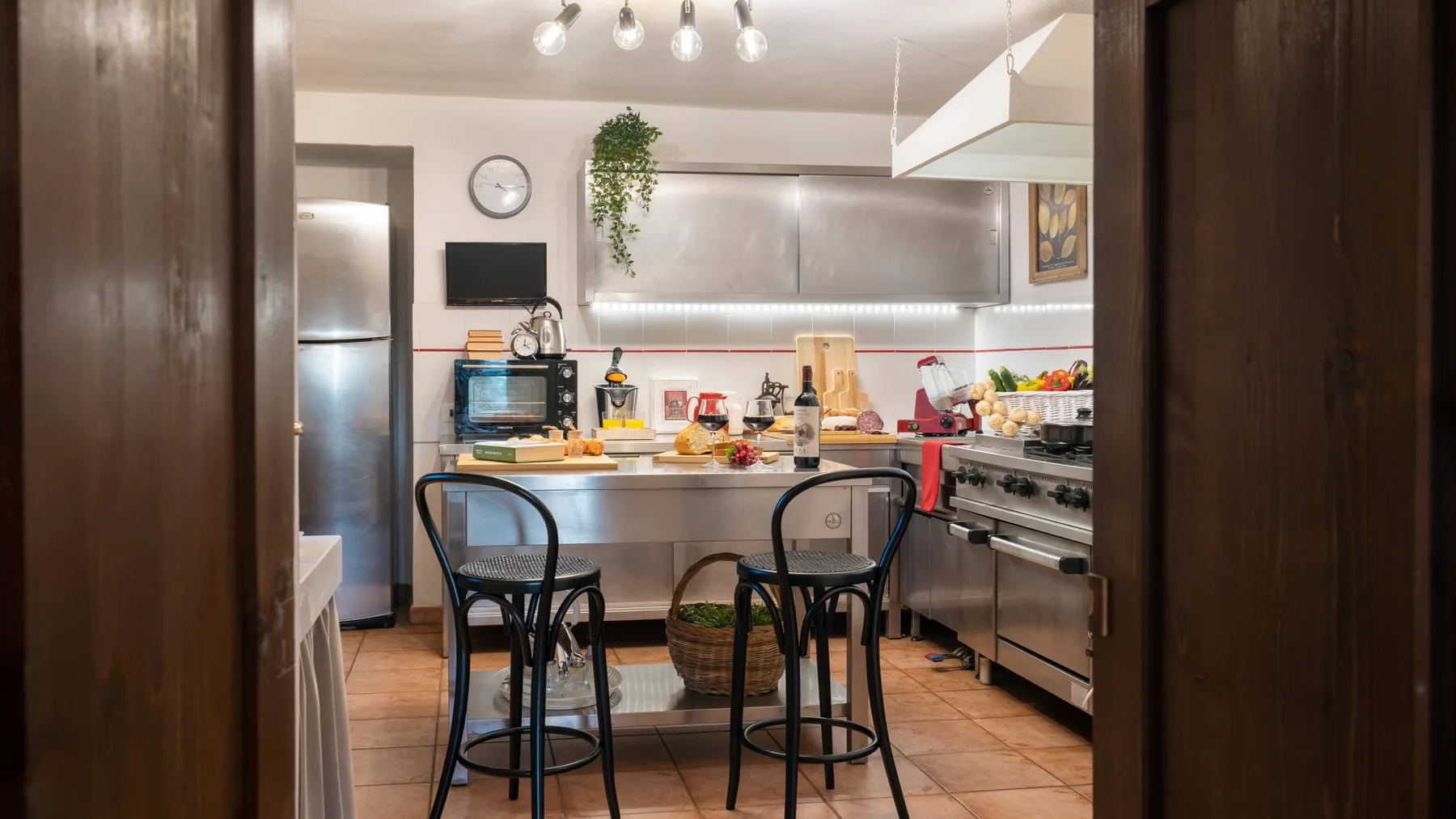 Una cocina con una barra larga, asientos altos y electrodomésticos de acero inoxidable.