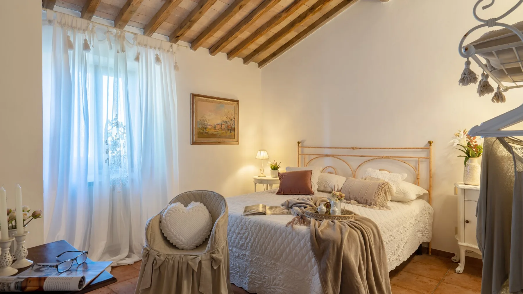 Un dormitorio con una cama doble, una ventana con cortinas y vigas a la vista.