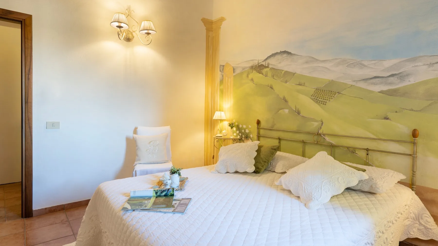 Un dormitorio con una cama bajo un mural de colinas onduladas.