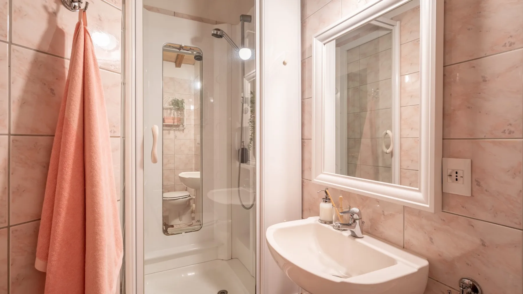 Un baño con azulejos, lavabo, espejo y ducha de vidrio.