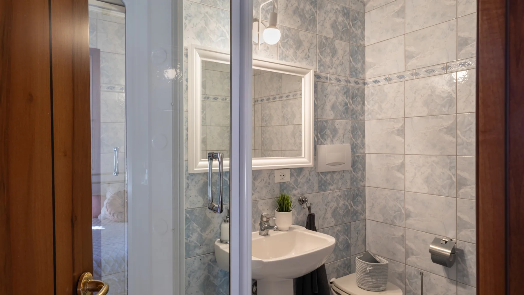 Un baño con azulejos, lavabo, espejo e inodoro.