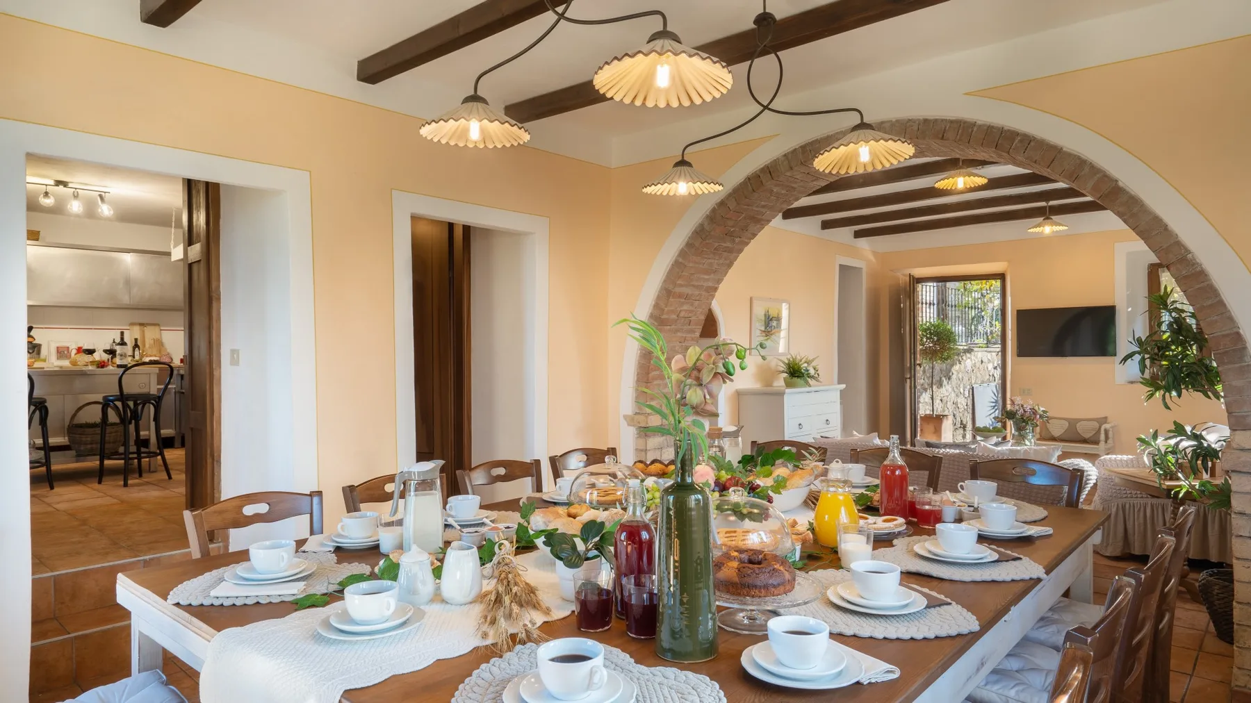 Comedor preparado con vajilla y comida, abierto a una sala de estar.