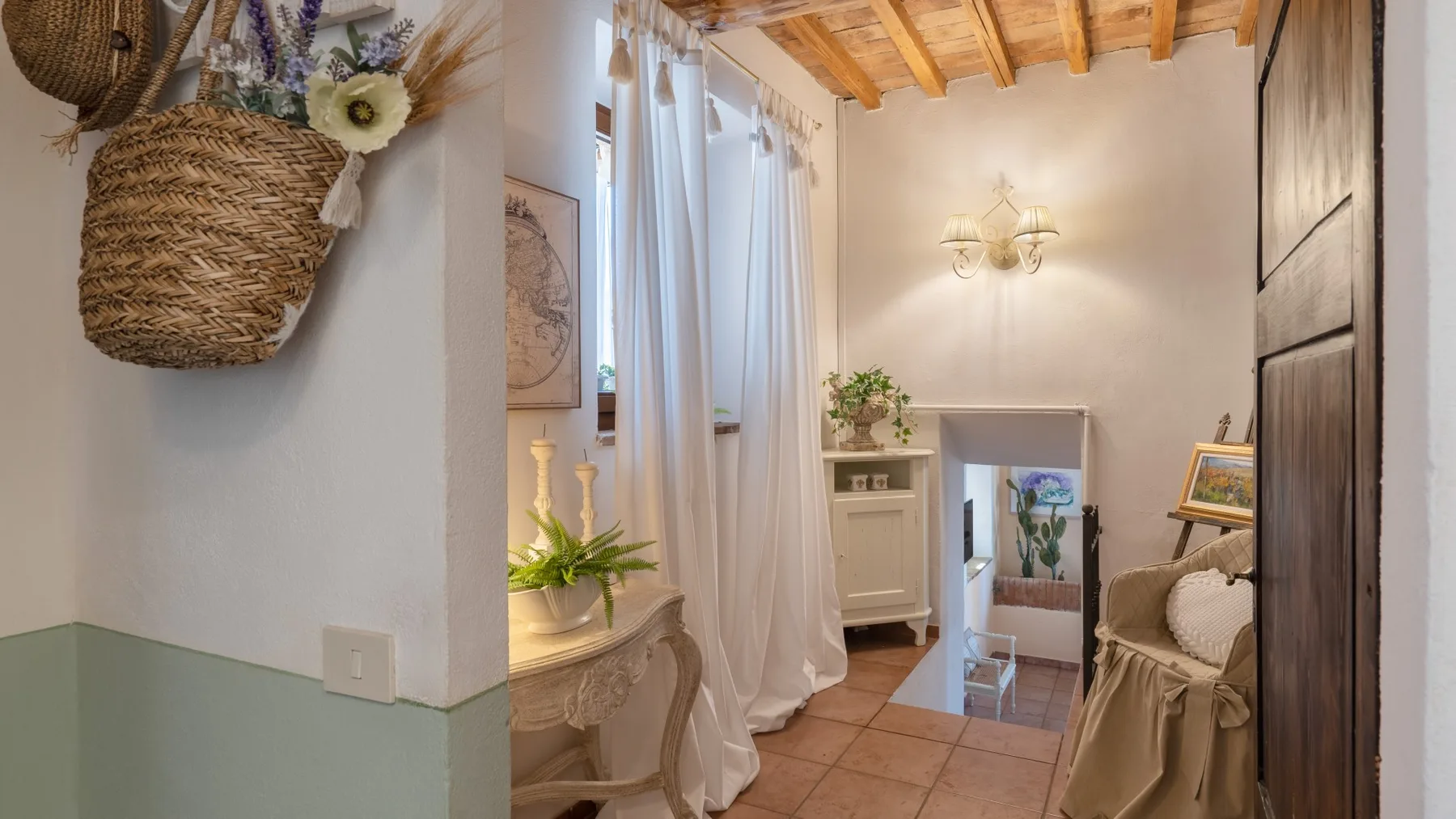 Una acogedora zona de estar con un mueble pequeño, una silla y cortinas translúcidas.
