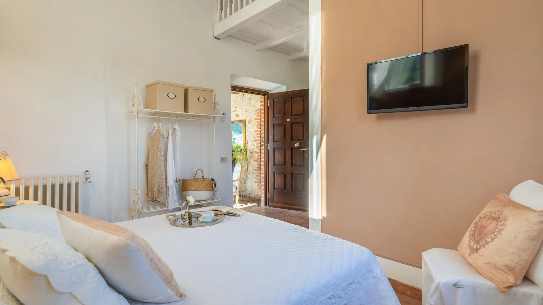 Un dormitorio con una cama, un televisor en la pared y una puerta abierta.
