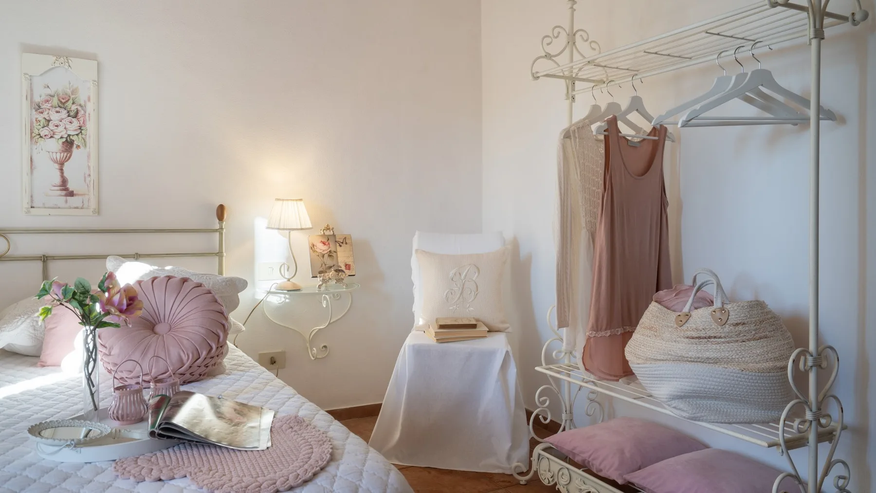 Un dormitorio con una cama junto a un perchero metálico y una mesita.