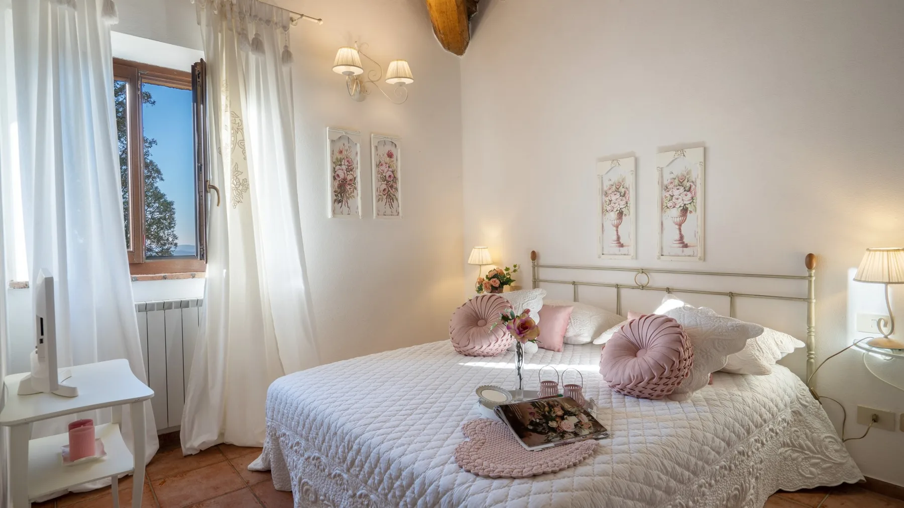 Un dormitorio con una cama bien arreglada, cojines decorativos y una ventana con cortinas.
