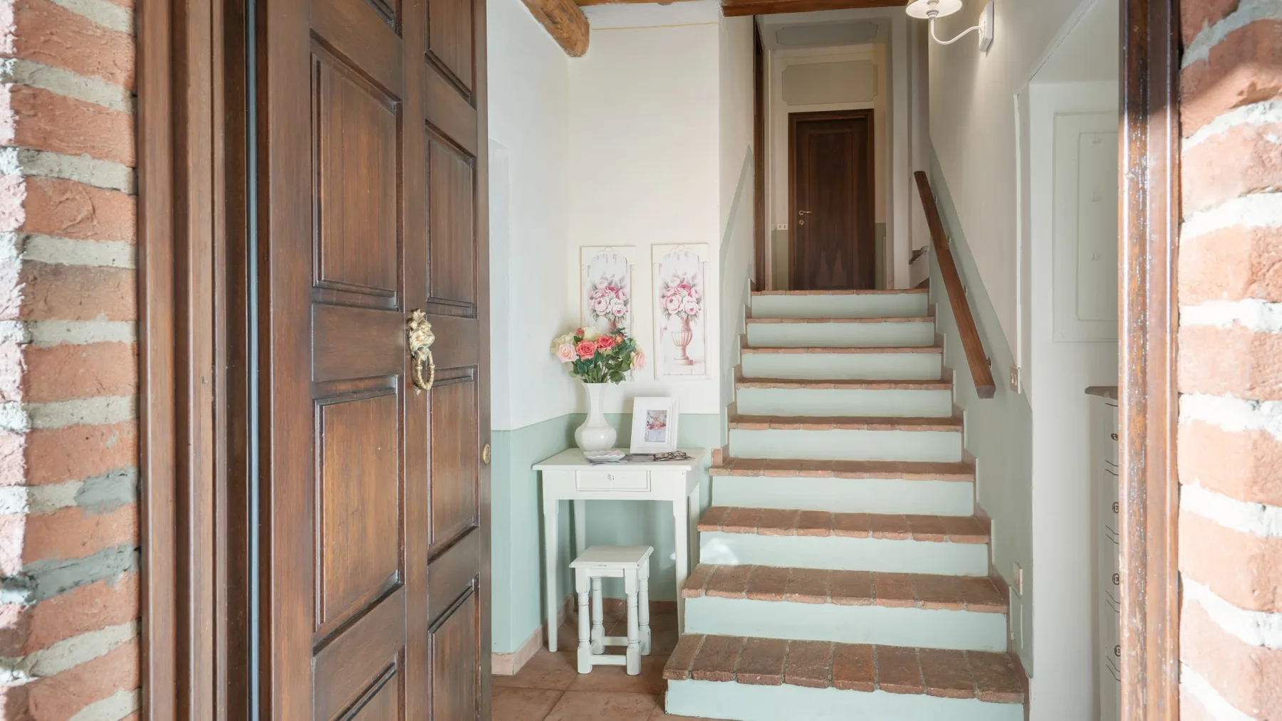 Una entrada interior da a una escalera, con una mesa pequeña al lado.