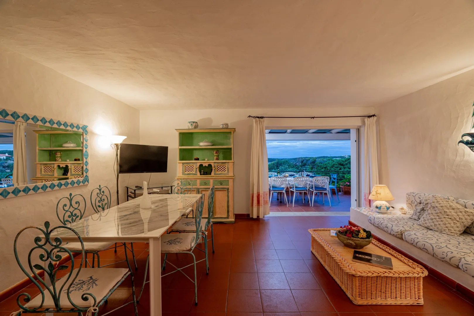 A living and dining room opens onto a terrace with outdoor seating.