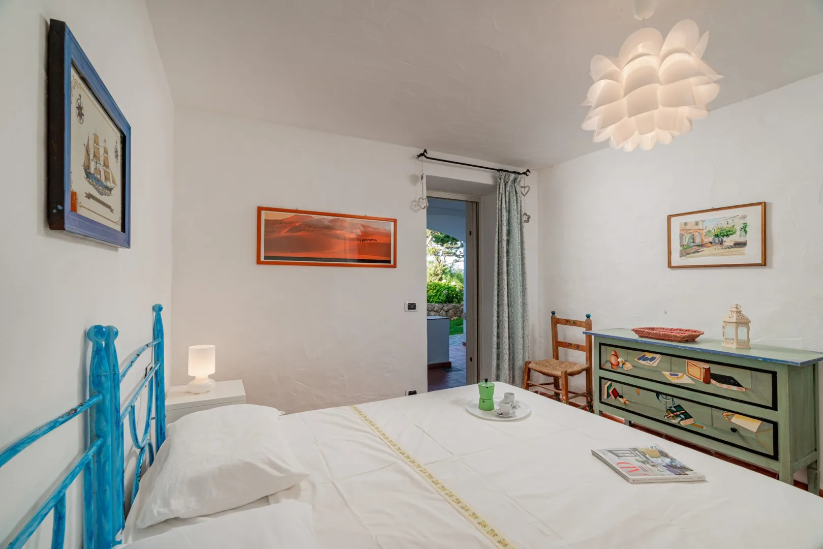 A bedroom with a neatly made bed, colorful furnishings, and an open doorway.