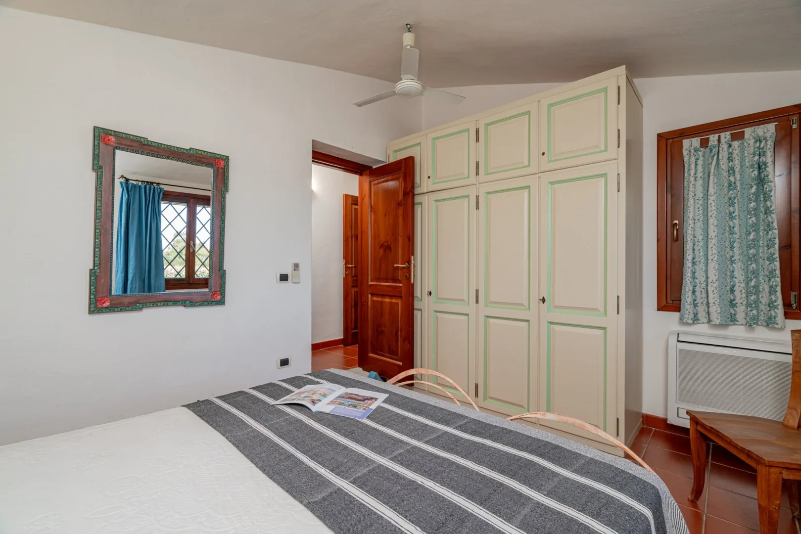 A bedroom with a bed, built-in cabinets, and an open wooden door.