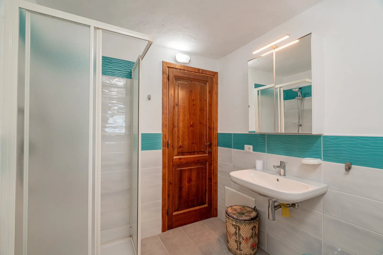 A bathroom with a shower, sink, and wooden door.
