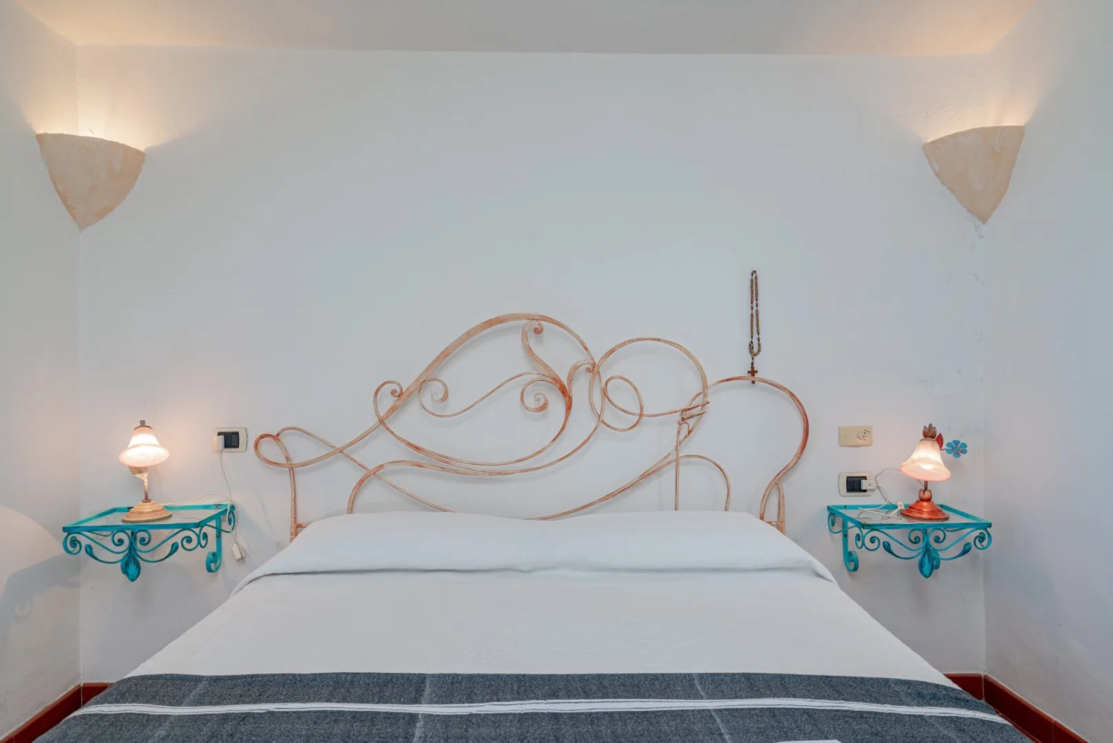A bedroom with a bed, decorative metal headboard, and matching bedside tables.