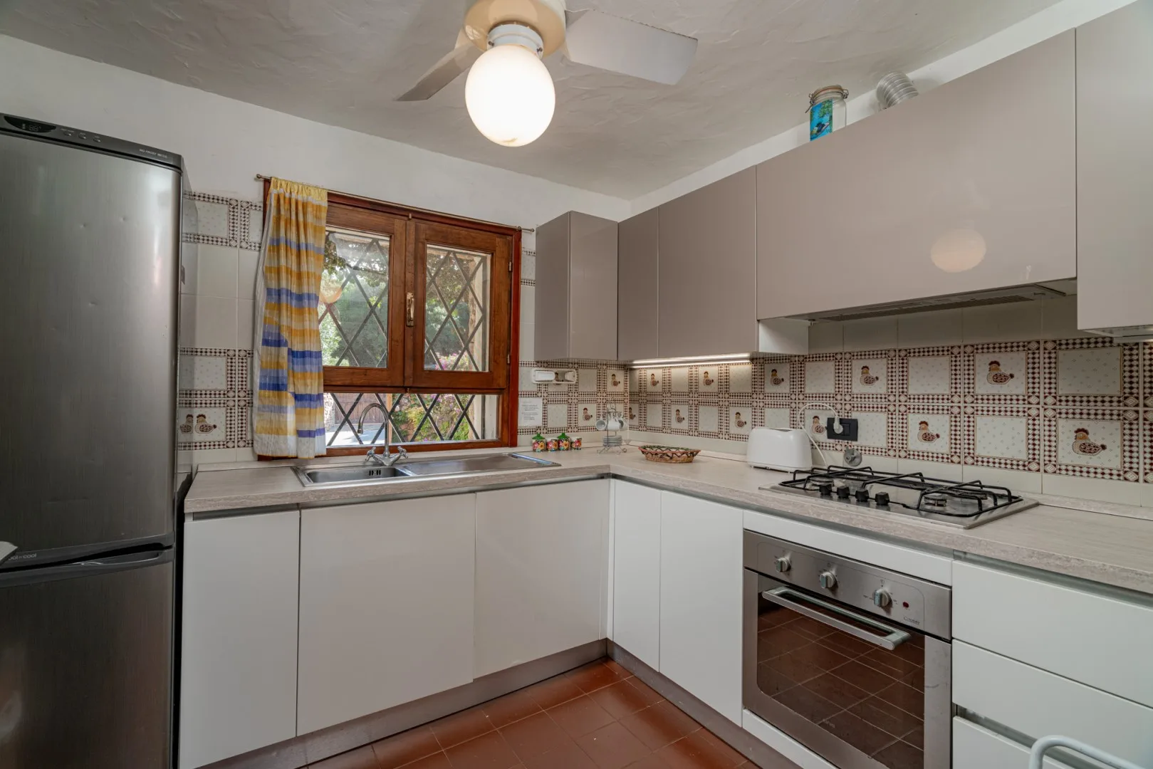 A kitchen with counters, cabinets, a stove, and a window.