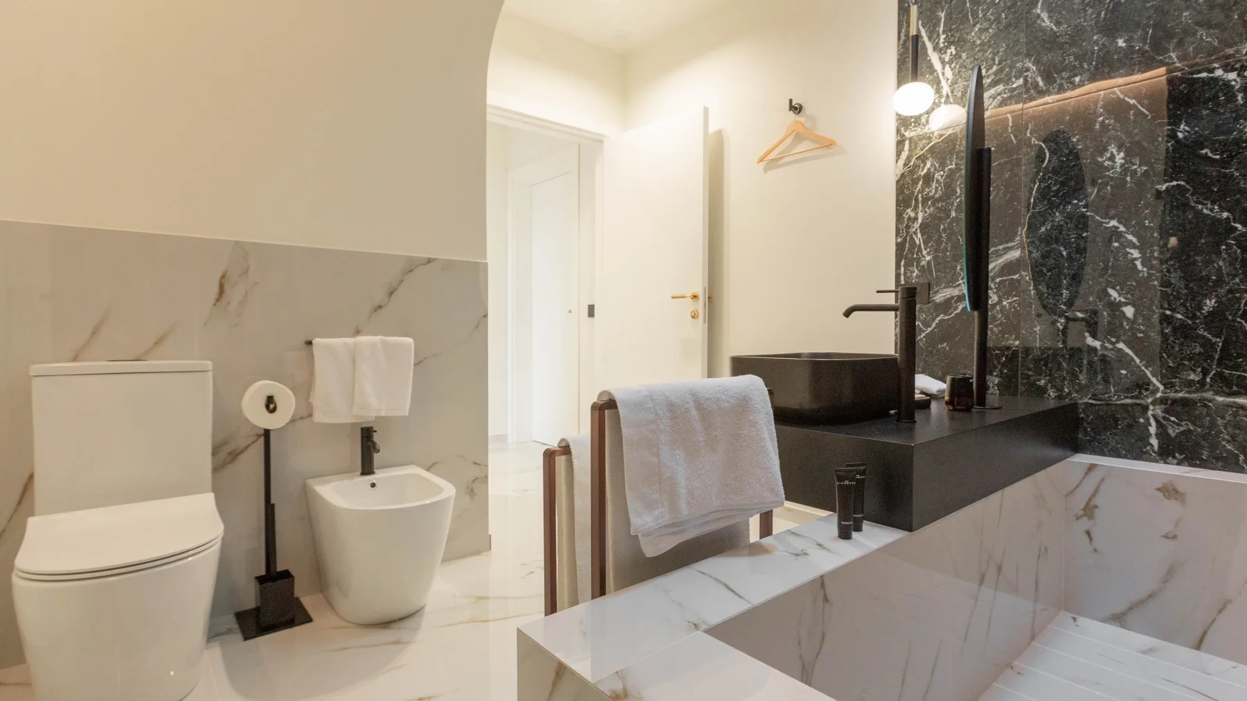 Un baño moderno con bañera, inodoro y lavabo junto a paneles oscuros de pared.