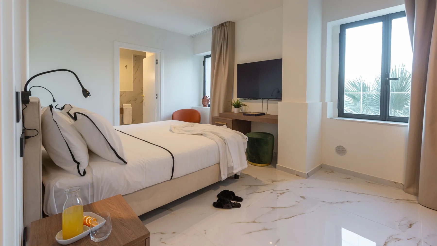 Un dormitorio luminoso con una cama, un televisor y una ventana grande.