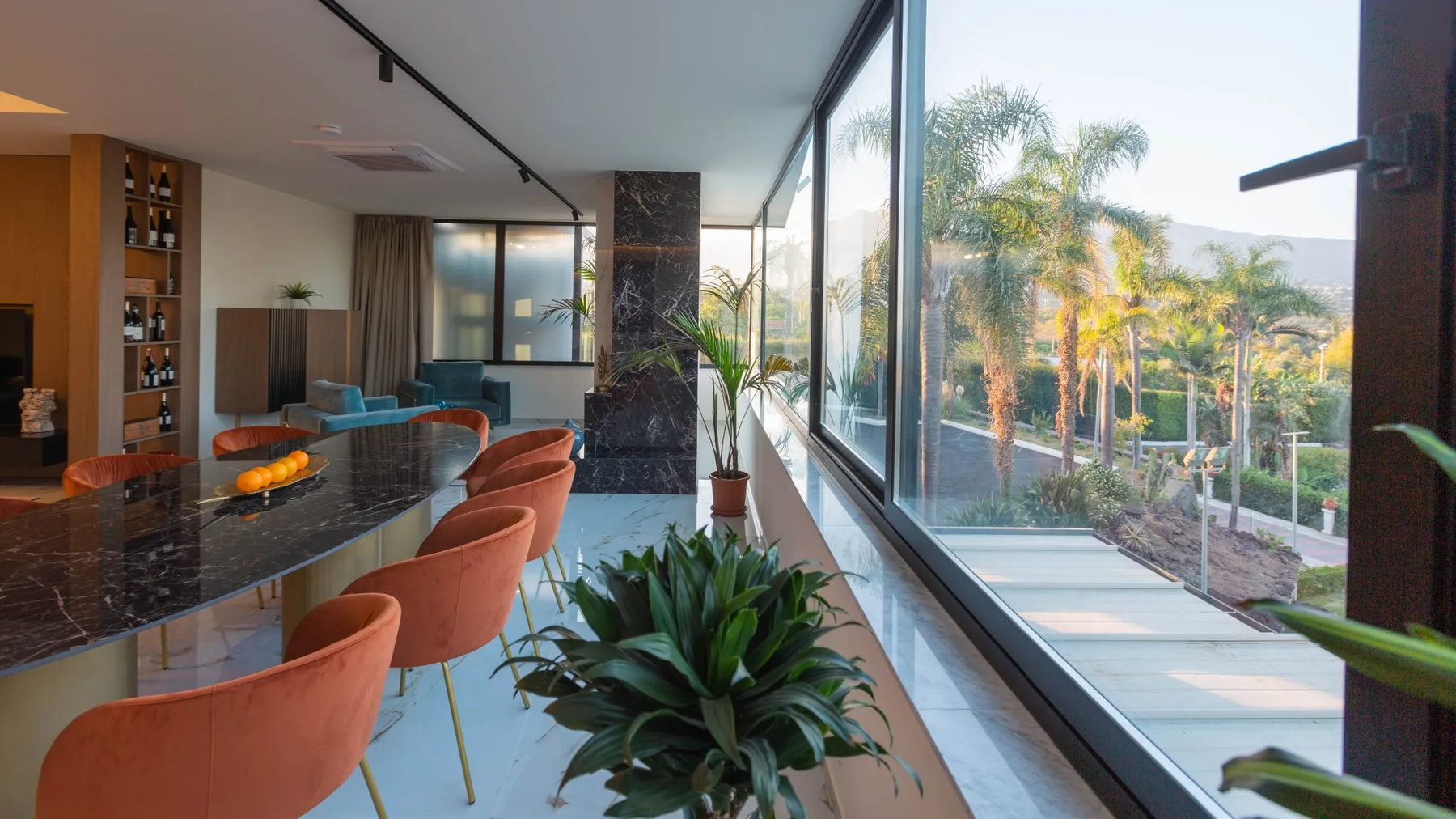 Una sala y comedor modernos se abren a un patio mediante ventanales de piso a techo.