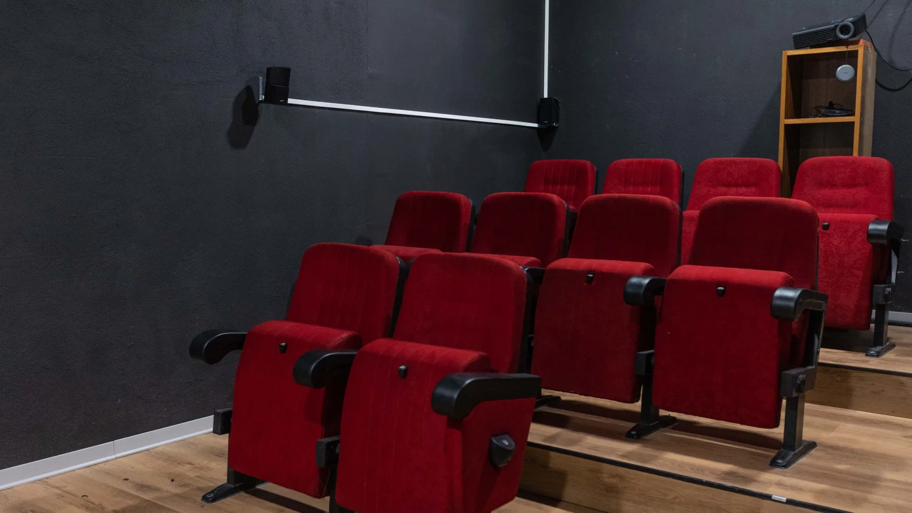 Una pequeña sala de cine con filas de asientos rojos orientados hacia el frente.