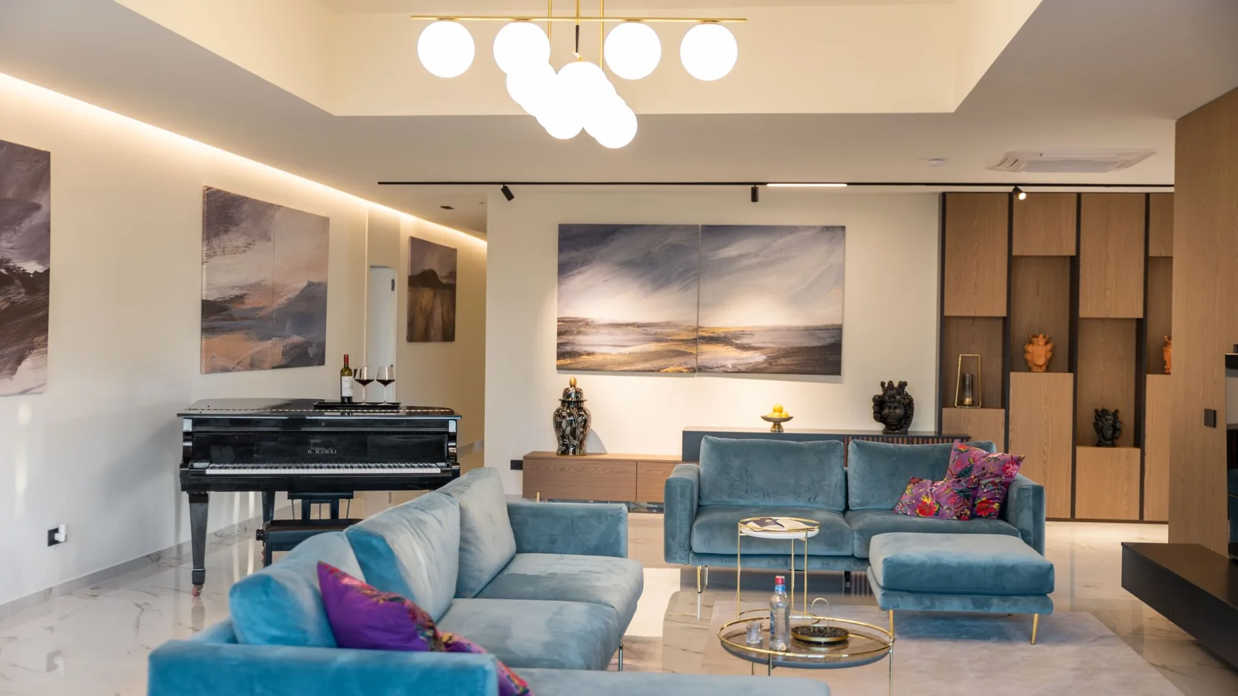 Una sala de estar con asientos azules, una mesa de centro y cuadros de paisajes.