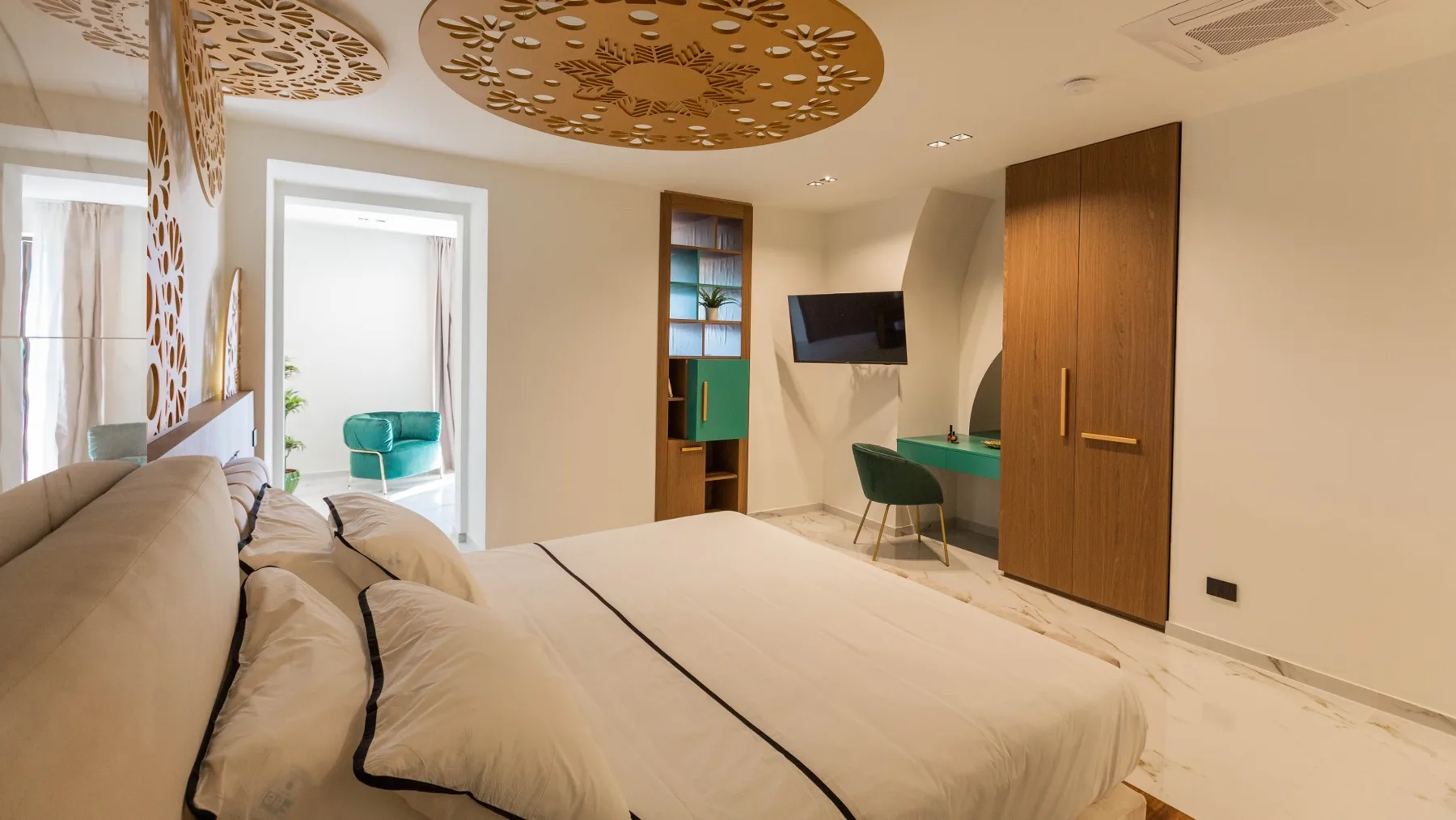 Un dormitorio con una cama grande y un escritorio junto a un televisor montado en la pared.