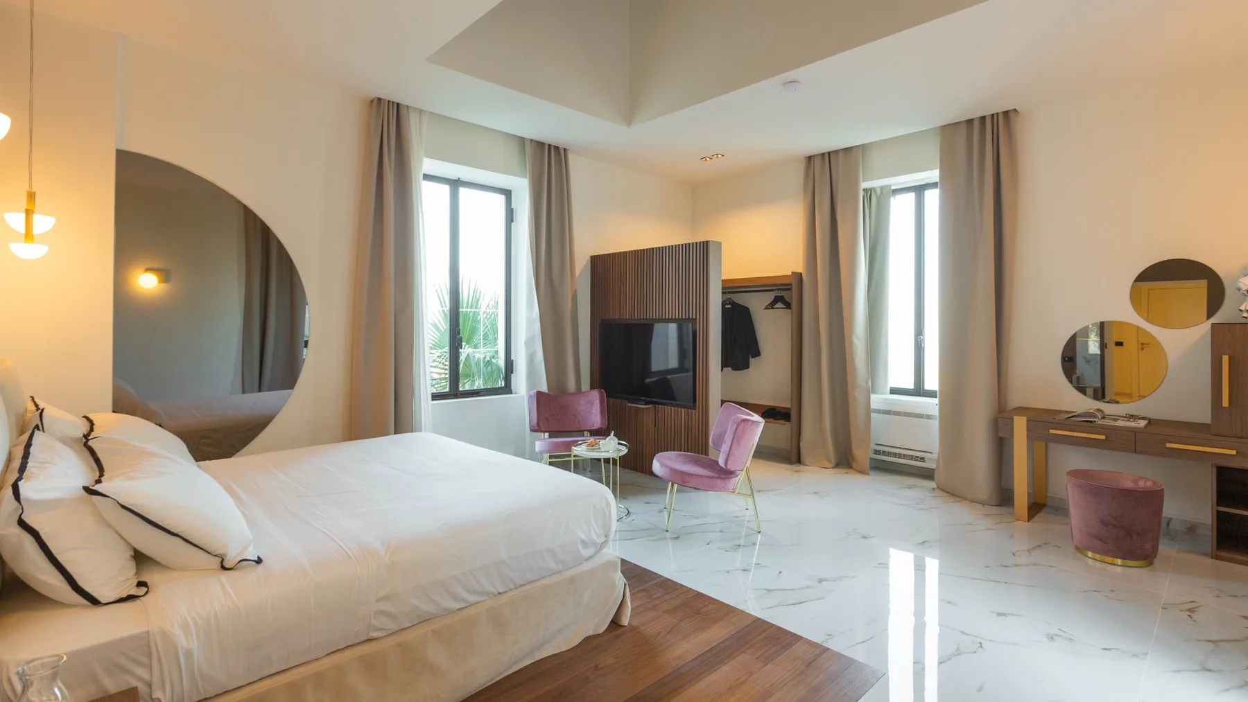 Un dormitorio con una cama grande, dos ventanas altas y un tocador.