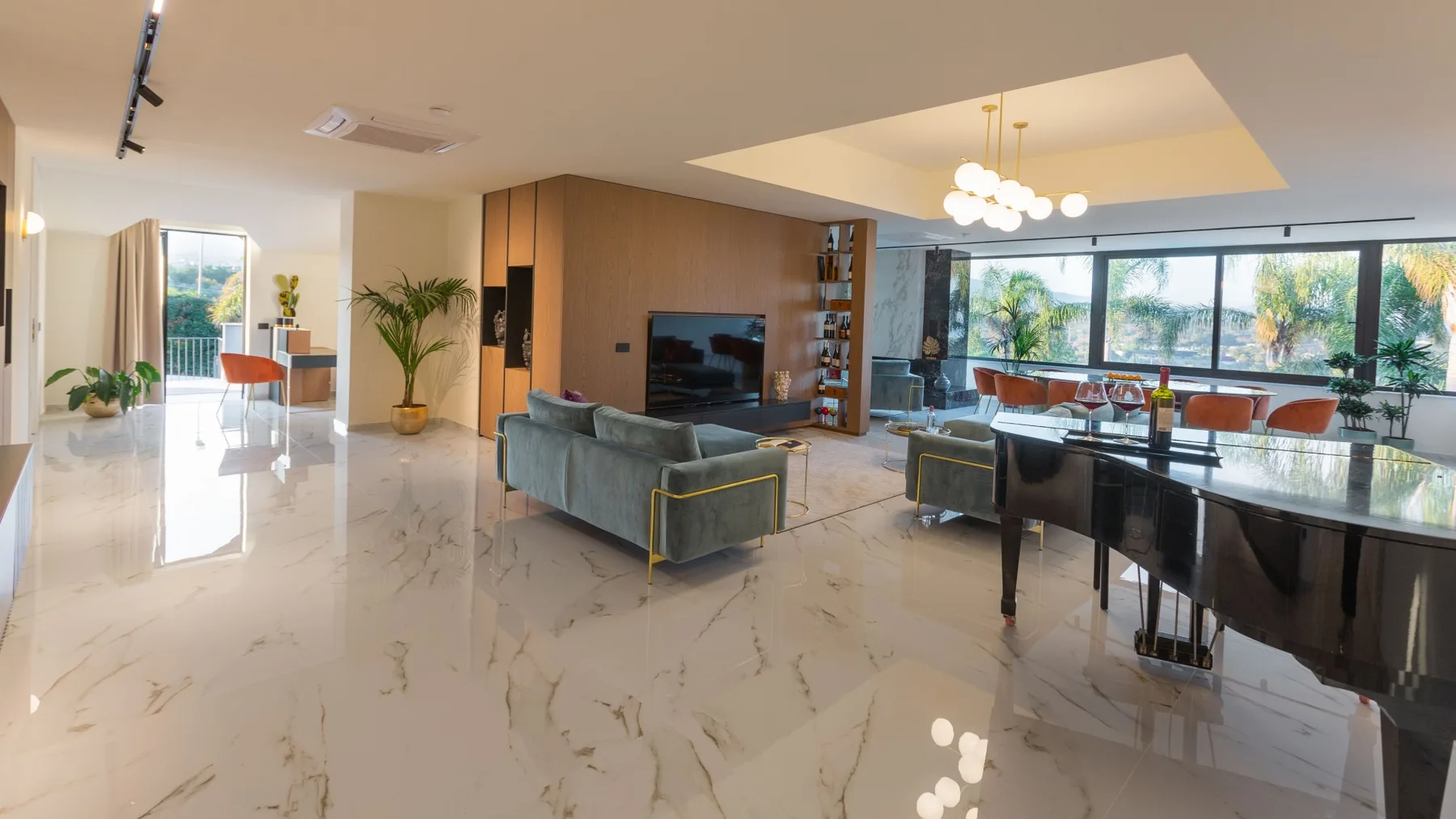 Una sala y comedor de planta abierta con televisor y ventanales.