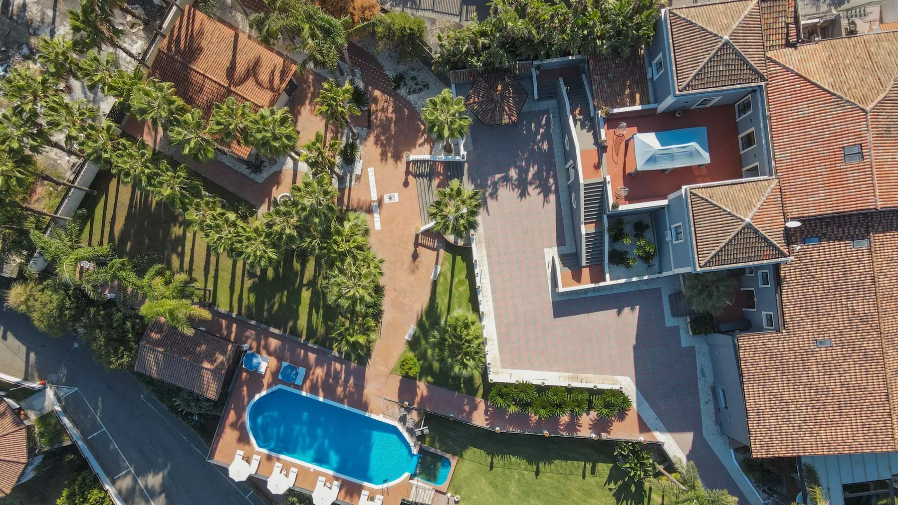 Vista aérea de una propiedad ajardinada con piscina y edificios alrededor.