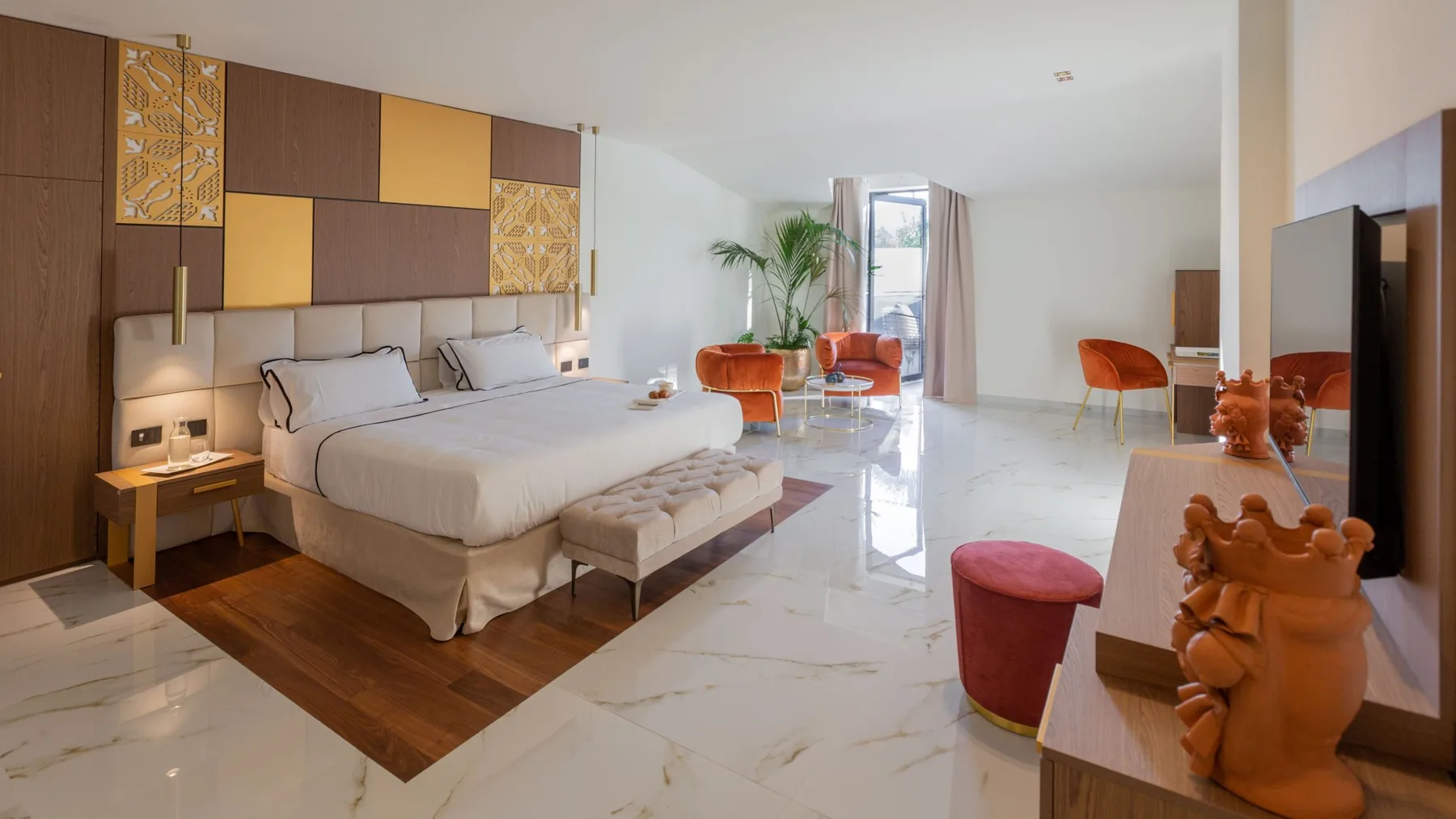 Un dormitorio amplio con una cama grande, paneles decorativos en la pared y asientos junto a la ventana.