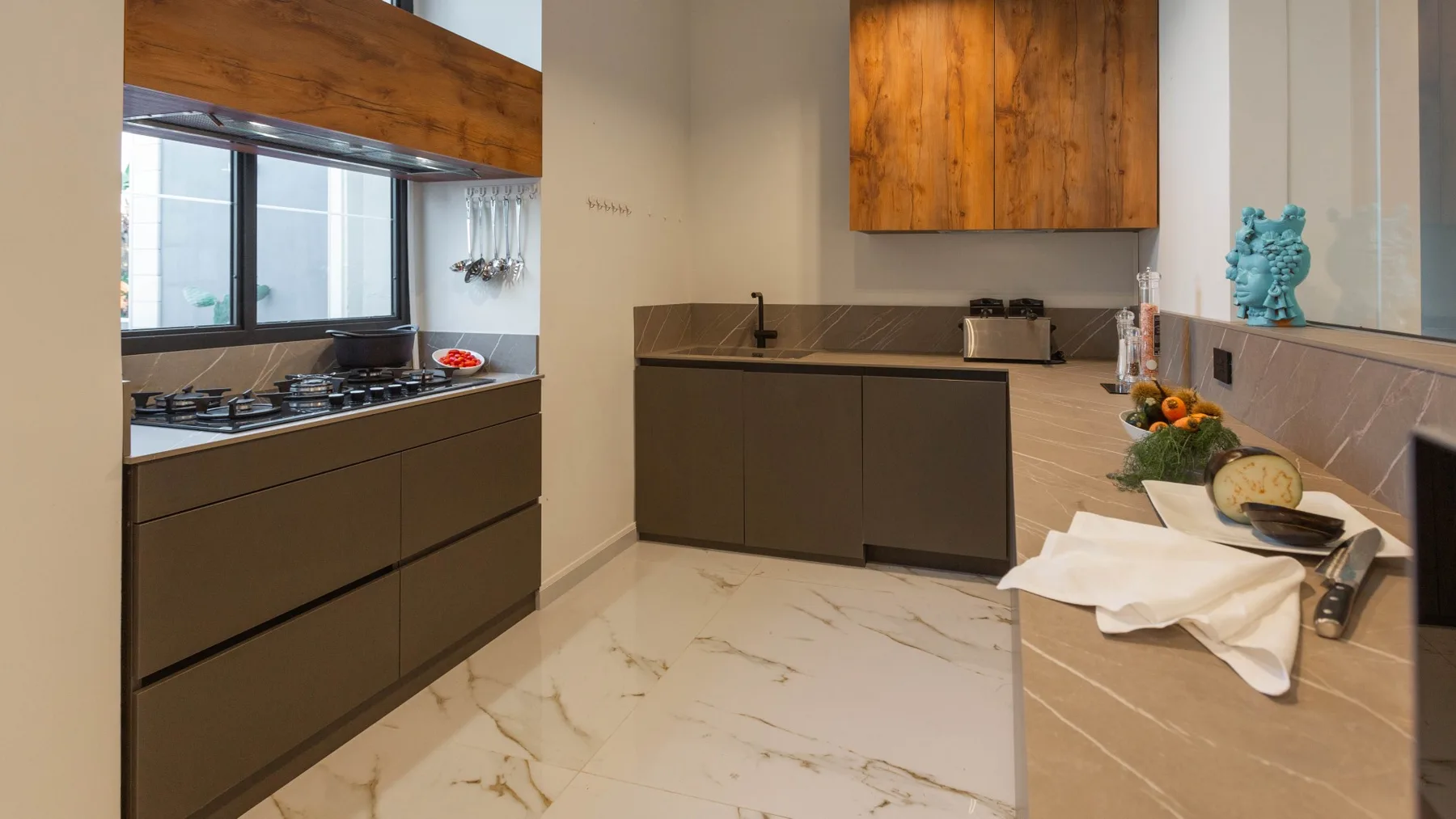 Una cocina moderna con gabinetes oscuros, una isla central y una encimera larga.