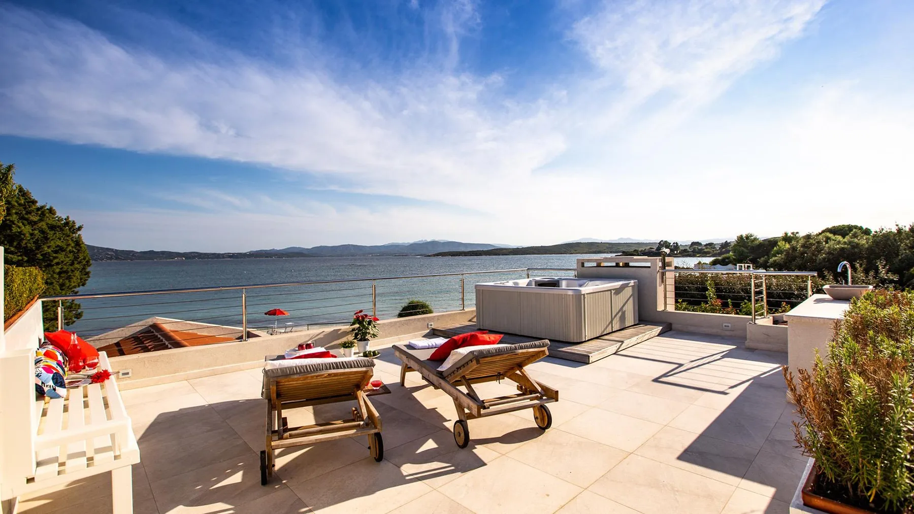 Una terraza soleada junto al agua tiene asientos y vistas al otro lado.