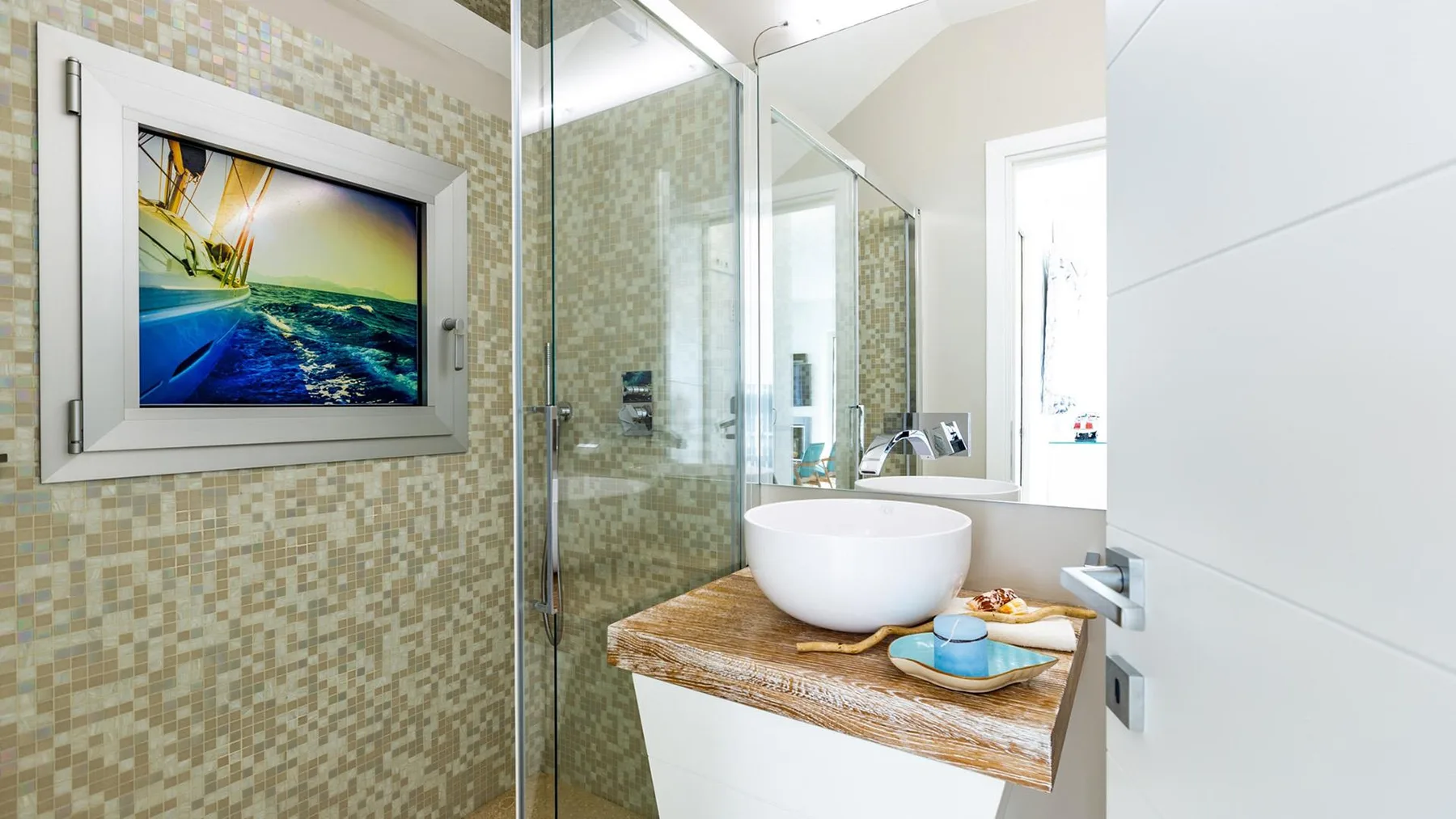 Un baño luminoso con una ducha de vidrio y un lavabo sobre la encimera.